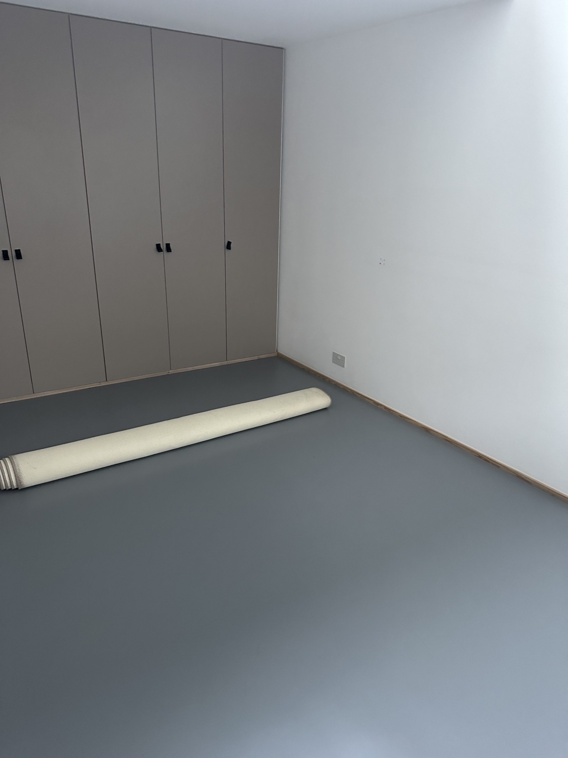 Finished grey resin floor in bedroom with built-in wardrobes in Kennington, South London