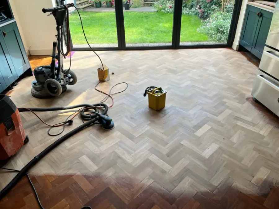 Dust-free floor sanding in progress on a herringbone wood floor using professional sanding equipment and vacuum system