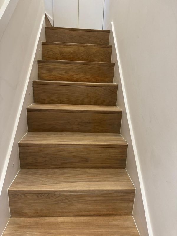 Oak stairs with refinished treads and risers after stair sanding in a narrow stairwell in London.