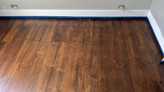 Wooden floorboards with a rich, dark finish achieved using Morrells Jacobean stain during floor restoration in Tooting.