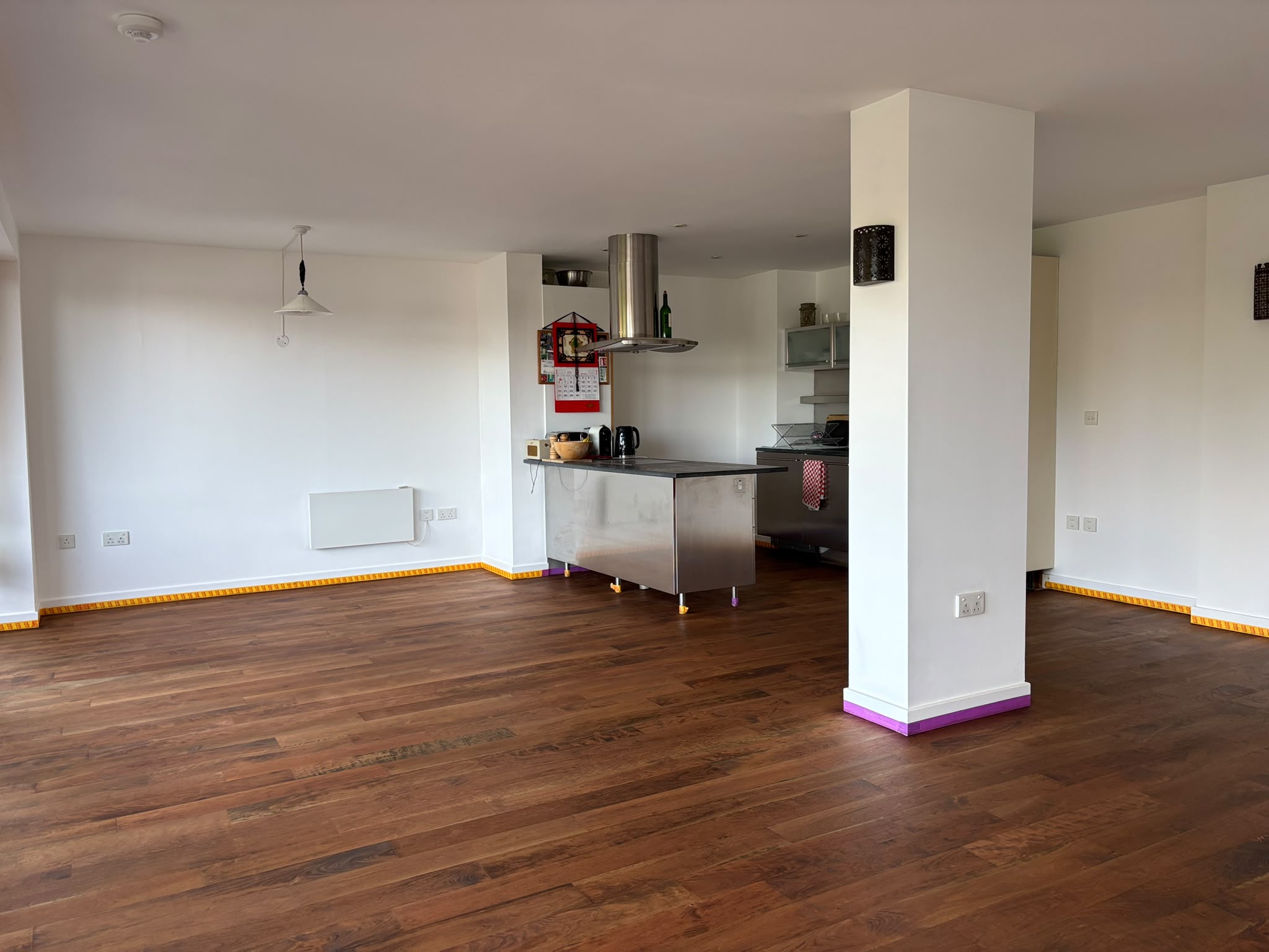 Open-plan kitchen and living space with a newly finished dark hardwood floor and a stainless steel kitchen island