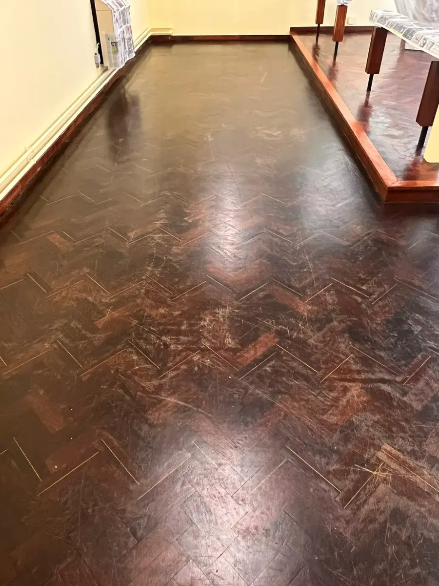 Worn and scratched Wenge parquet flooring before sanding in a church in Heston