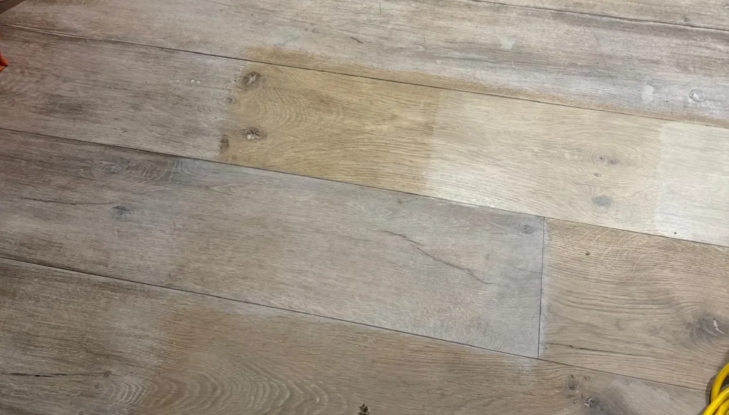 Close-up of oak flooring in Kensington showing samples of white finishes with varying tones during the restoration process.