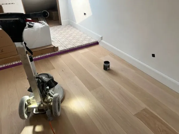 Dust-free floor sanding machine refinishing a light wood floor in a modern home