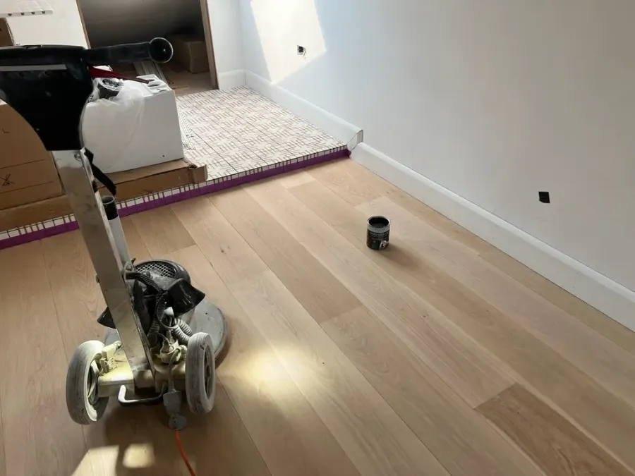 Dust free floor sanding London using professional sanding machine on oak wooden floor in home interior