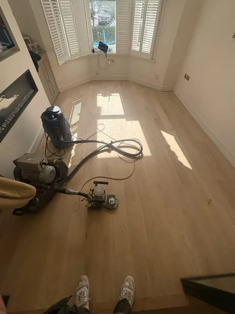 dust free floor sanding machine connected to extraction system during wood floor sanding in a residential room