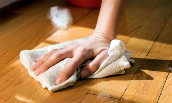 hand wiping the wooden floor with a towel