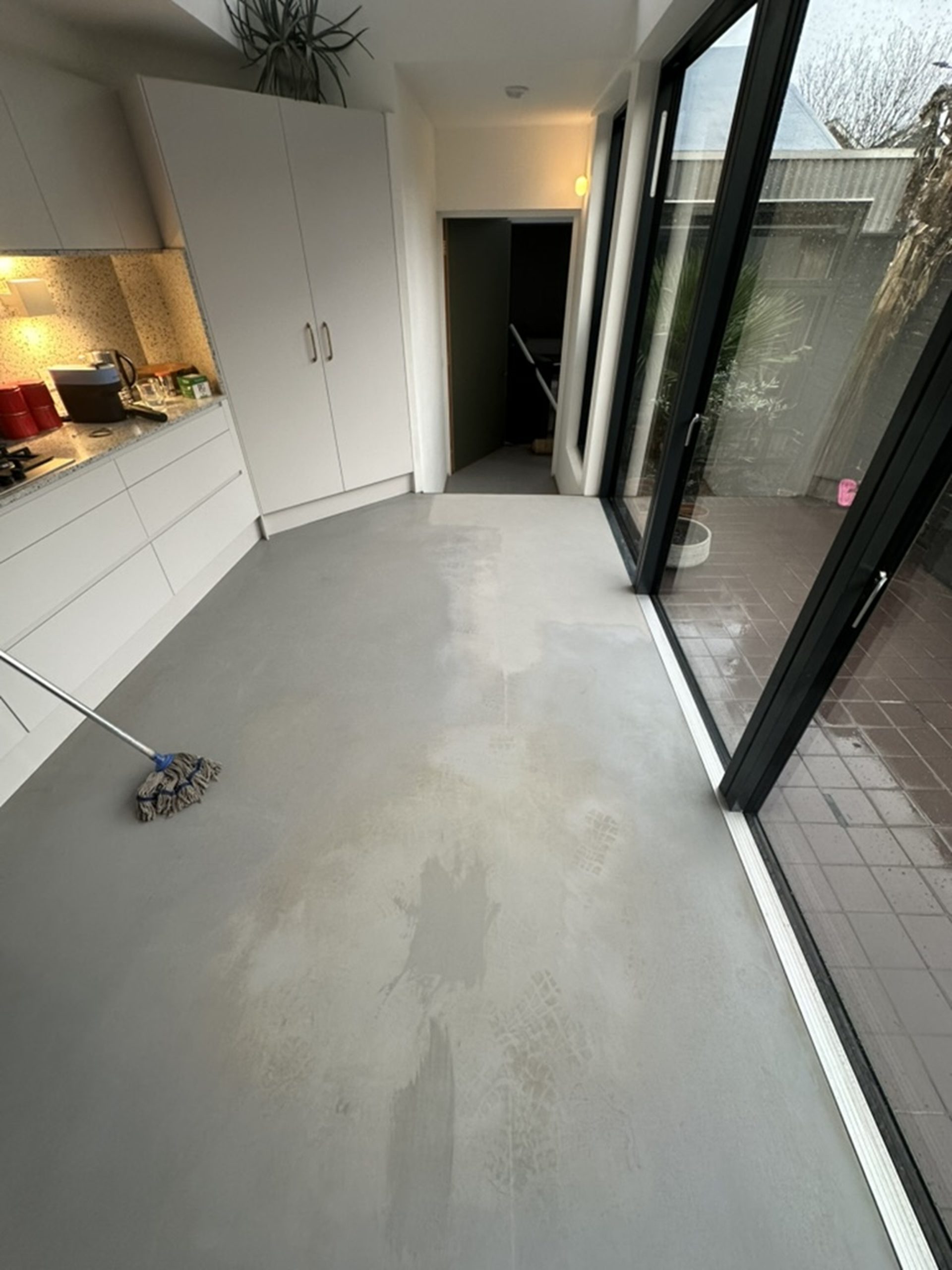 Failed grey resin kitchen floor showing moisture damage in Kennington, South London