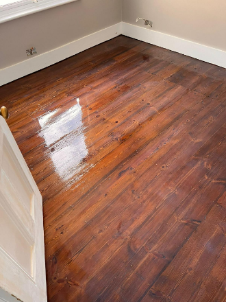 Freshly lacquered wooden floorboards in Tooting with a rich stain, restored to a smooth and polished finish.