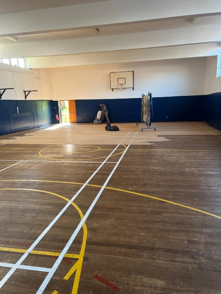 School sports hall undergoing meticulous sanding and precision lining in Croydon, showcasing the restoration process.