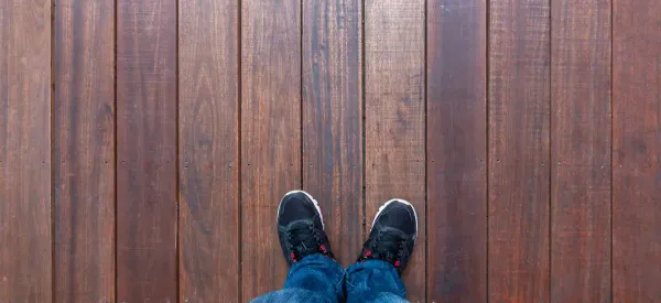 A person looking down at their wooden floor, reflecting on choosing the right restoration contractor.