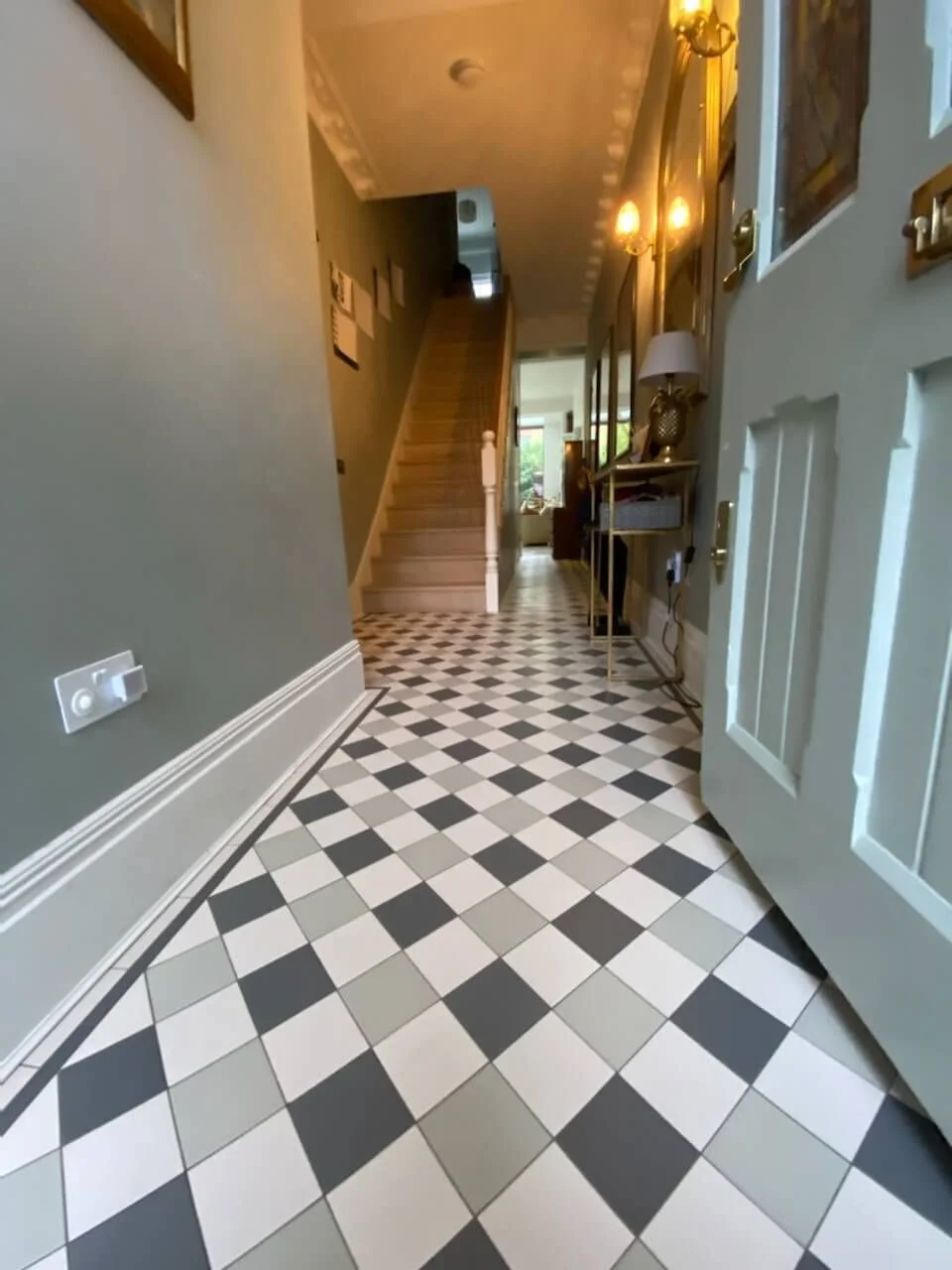 Victorian hallway with classic black and white checkered tiles, featuring a staircase and elegant decor, showcasing timeless style in London.